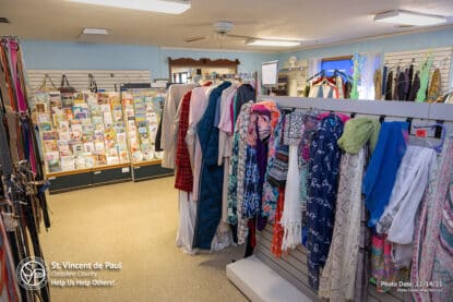 Women's scarves and belts at SVDP Ozaukee County in Port Washington, WI. Greeting card rack in the background.