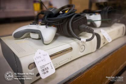 A used XBOX 360 for sale in Port Washington, WI at St. Vincent de Paul. Excellent condition video game console with a white controller and a black cable.